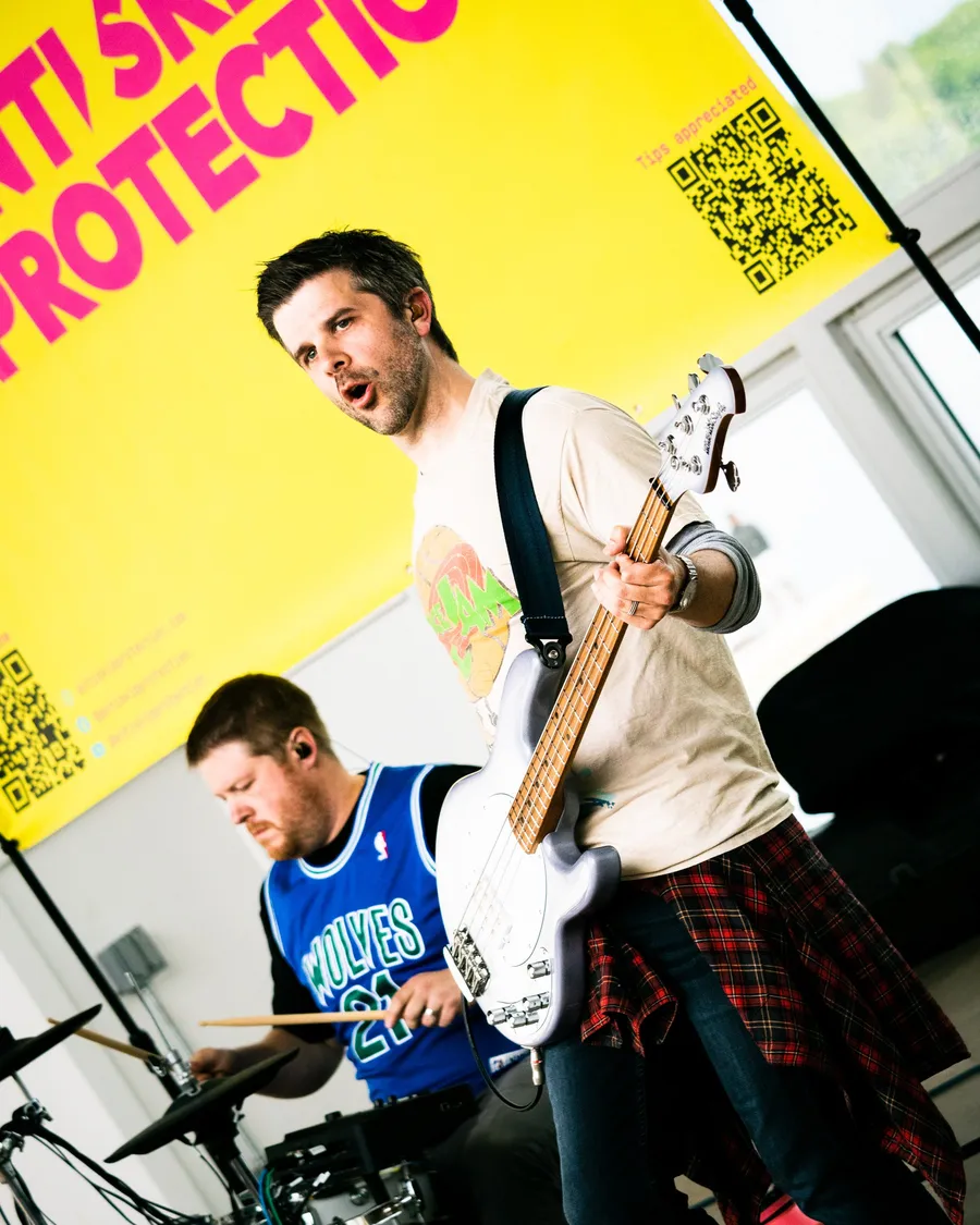 Bassist in a Timberwolves jersey mid-song in front of a yellow banner