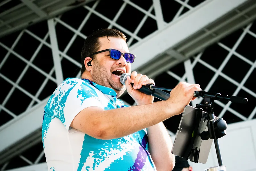 Lead singer mid-chorus in a 90s jazz-cup shirt and blue shades
